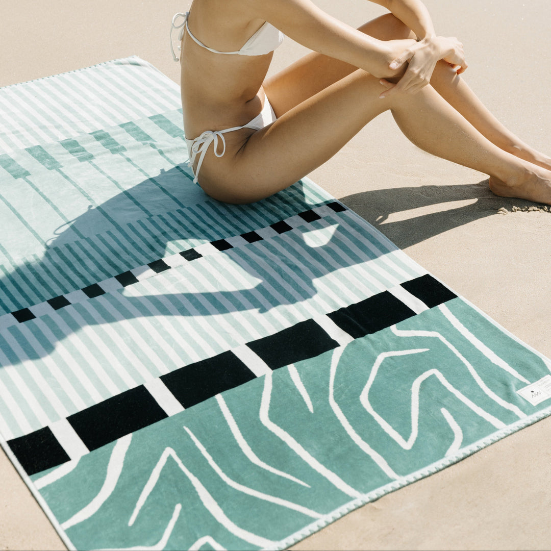 Woman in a bikini sitting on a beach towel at the beach