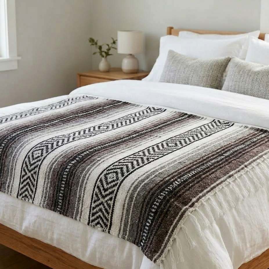 Bed with patterned throw blanket and white bedding in a bedroom setting.