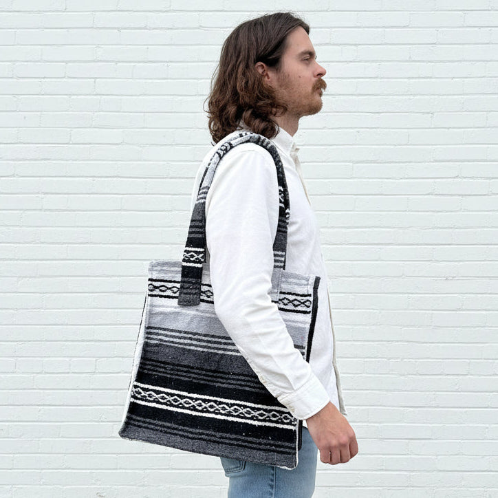 Person holding a black and white patterned bag against a corrugated metal background