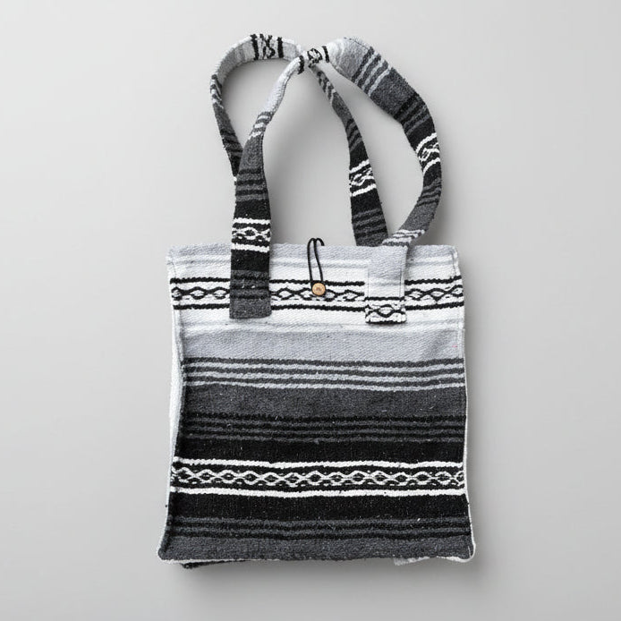 Striped handbag with patterned handles on a beige background