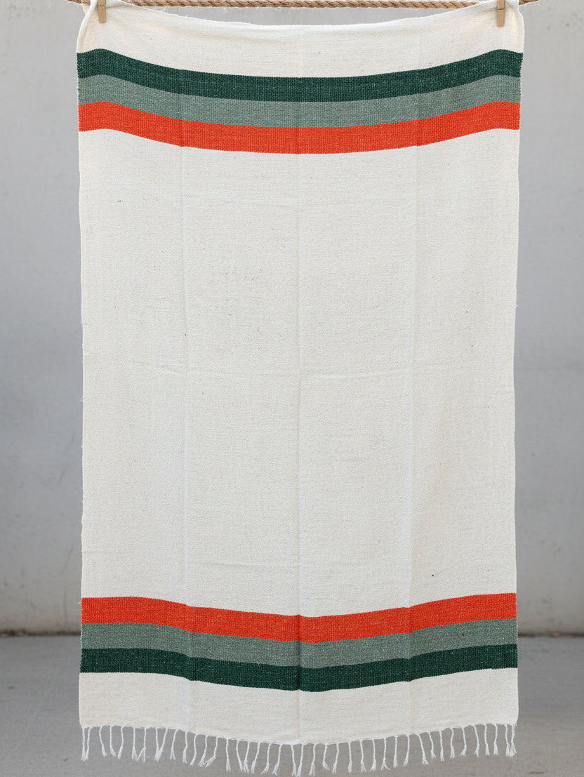 White blanket with green and orange stripes on a dark textured surface