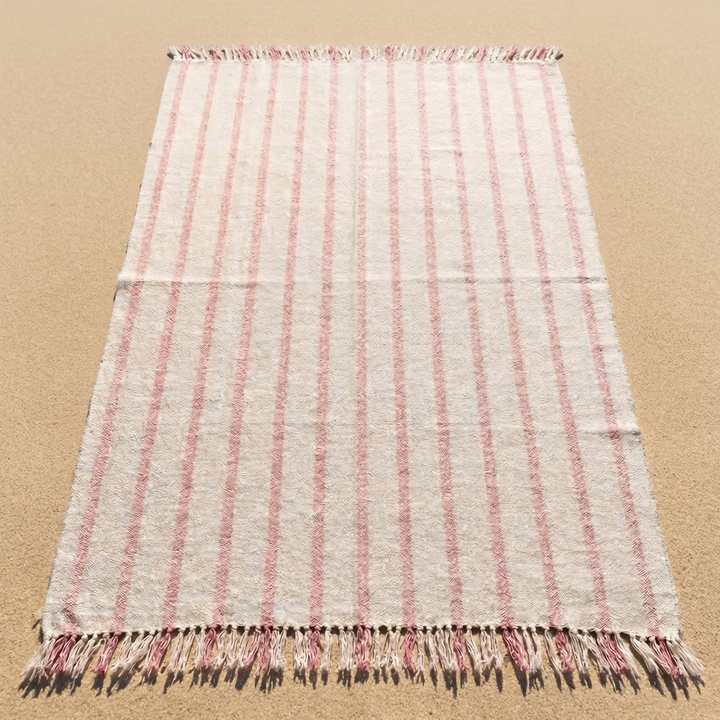 Striped blanket with fringes on a sandy surface