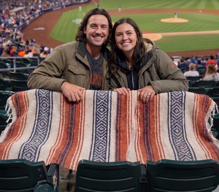 Two people posing with a blanket at a baseball game in Petco Park.