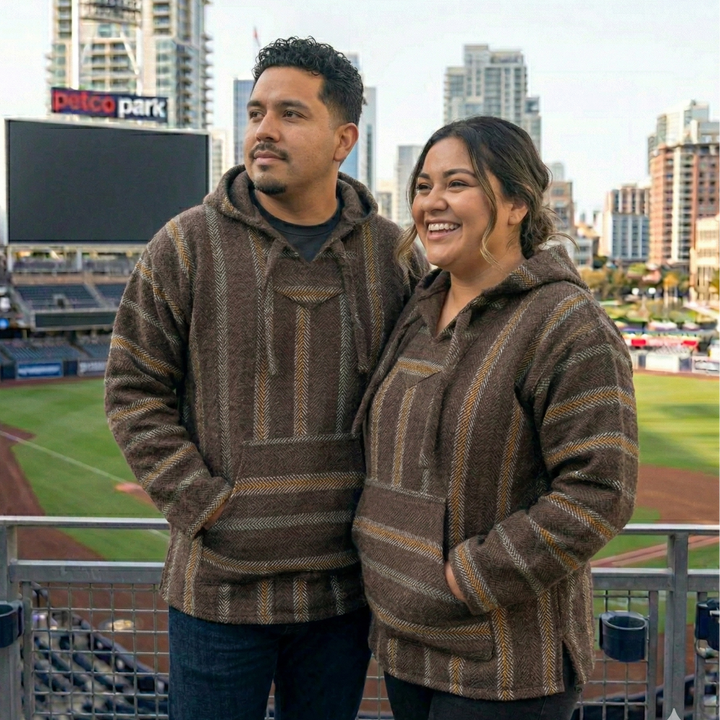 Two people wearing matching padres hoodies at a baseball stadium with 'Petco Park' in the background.