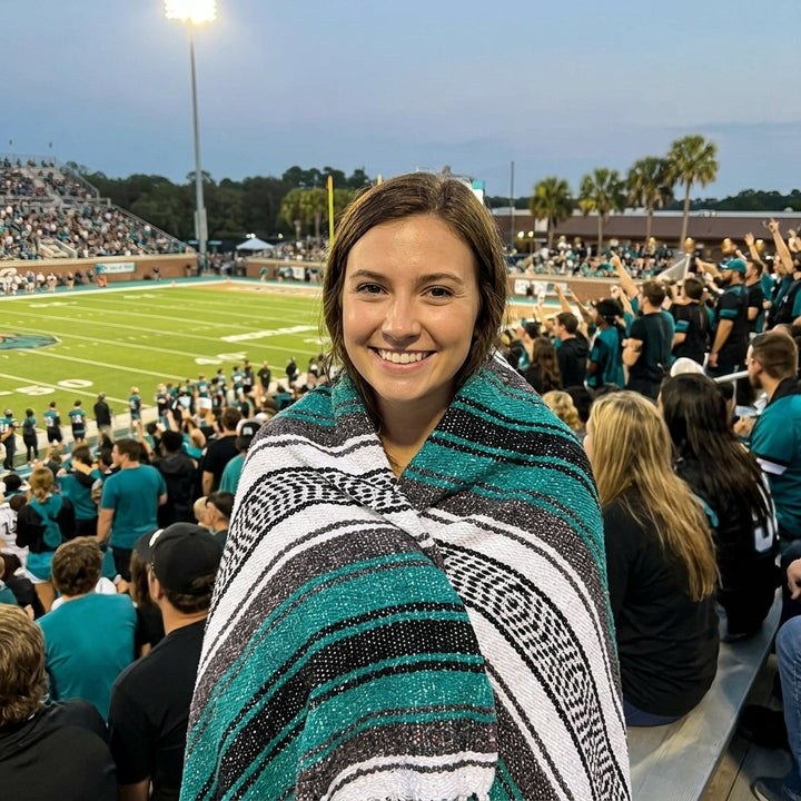 Fan wrapped in a Mexican stadium blanket in Coastal Carolina University colors at a college football game