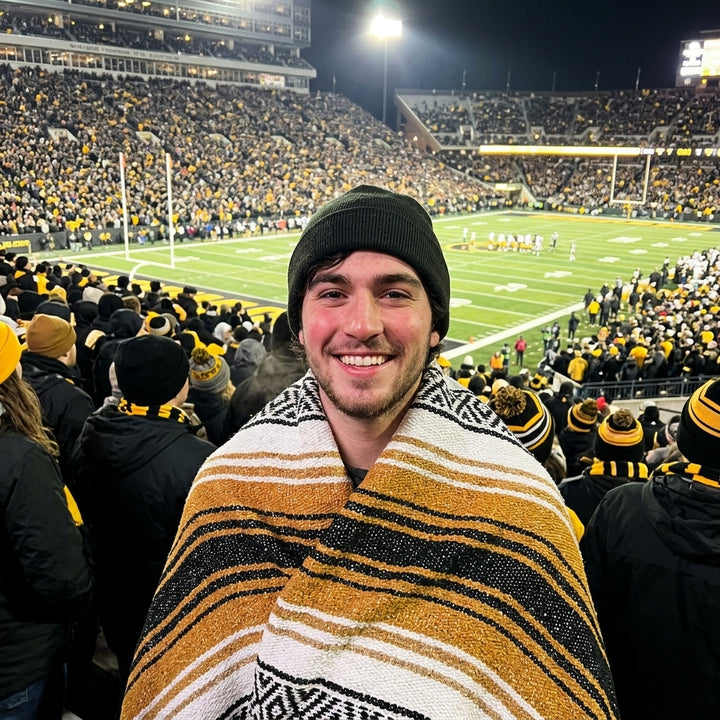 Fan wrapped in a Mexican stadium blanket in University of Iowa colors at a college football game