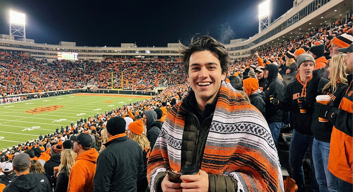 Fan wrapped in a Mexican stadium blanket in Oklahoma State University colors at a college football game