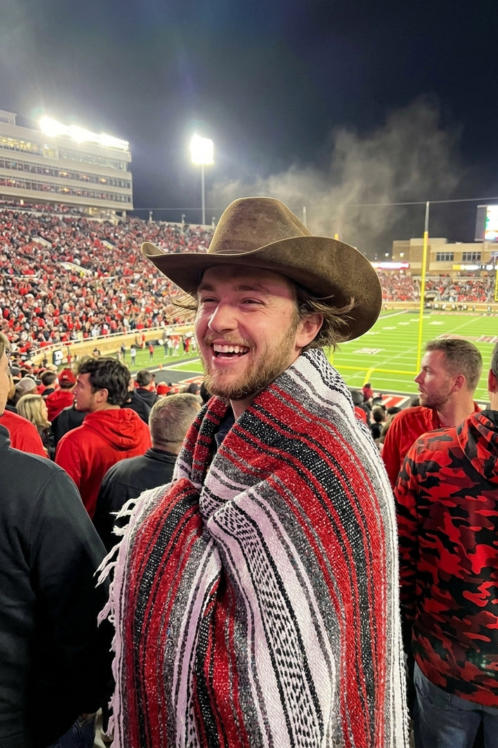 Fan wrapped in a Mexican stadium blanket in Texas Tech University colors at a college football game