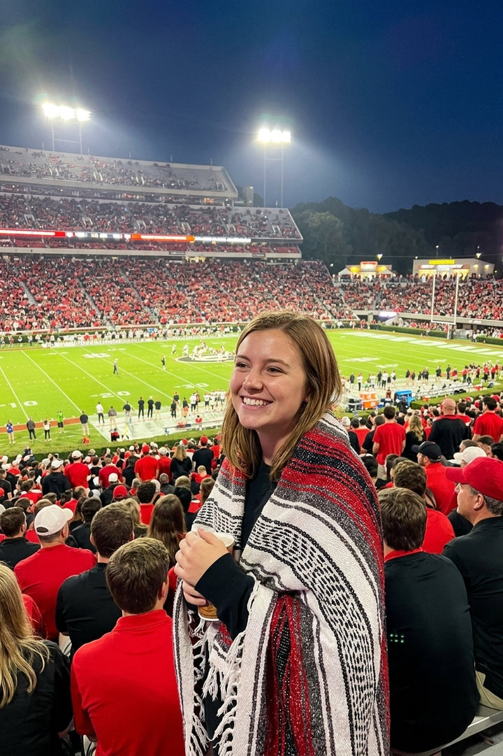 Fan wrapped in a Mexican stadium blanket in University of Georgia colors at a college football game