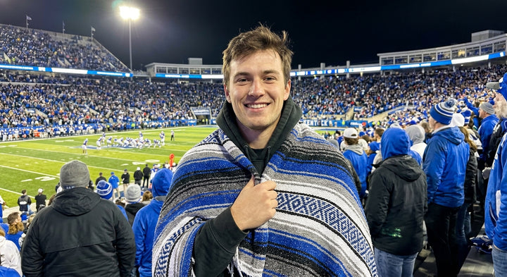 Fan wrapped in a Mexican stadium blanket in University of Kentucky colors at a college football game
