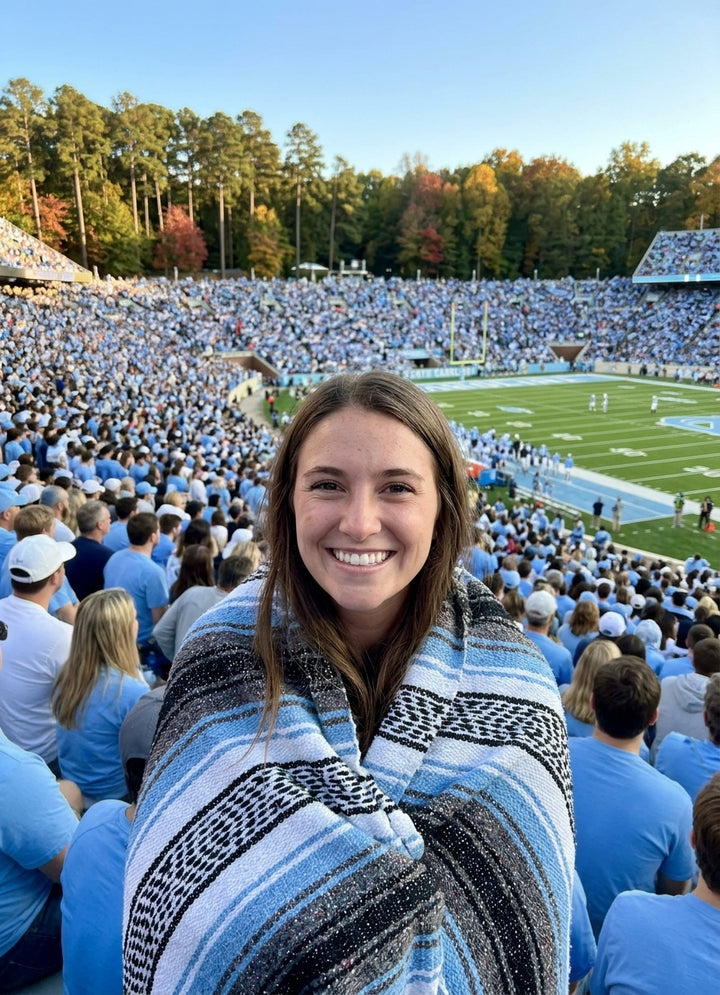 Fan wrapped in a Mexican stadium blanket in University of North Carolina colors at a college football game