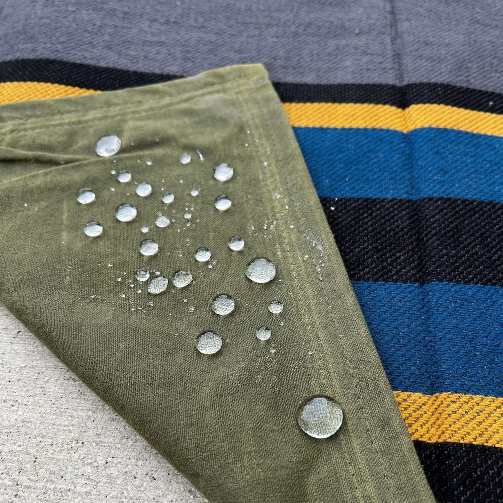 Green fabric with water droplets on a gray and yellow striped background