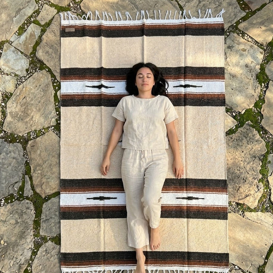 Woman lying on a striped rug on stone pavement
