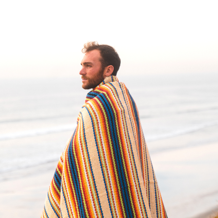 Model wearing the rainbow beach blanket around him 